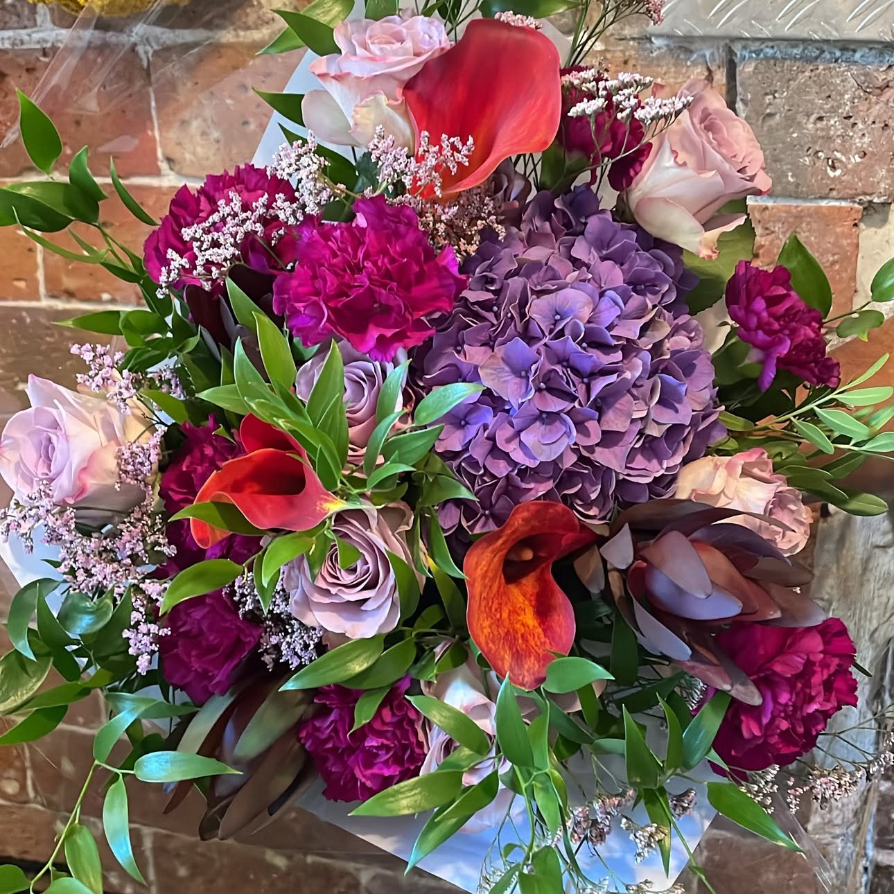 Bouquet d’hortensia mauve, œillets pourpres et arums orange