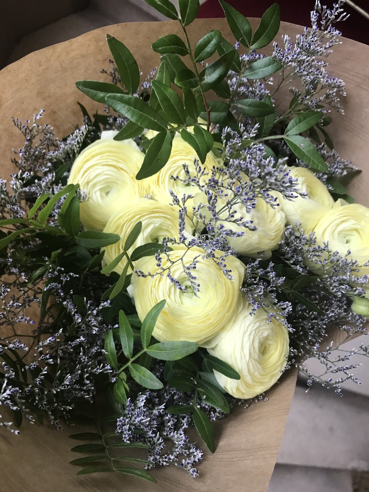 Renoncules jaune pâle, limonium et feuillage